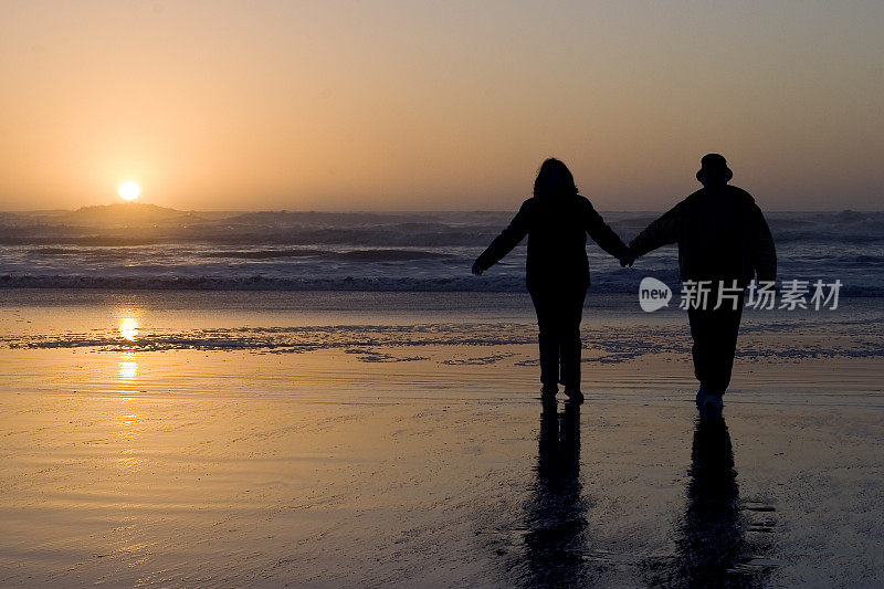 日落时分，一对浪漫的情侣在水边散步