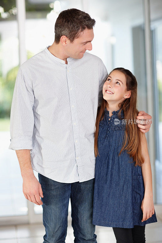 慈爱的父亲带着微笑的女儿一起站在家里