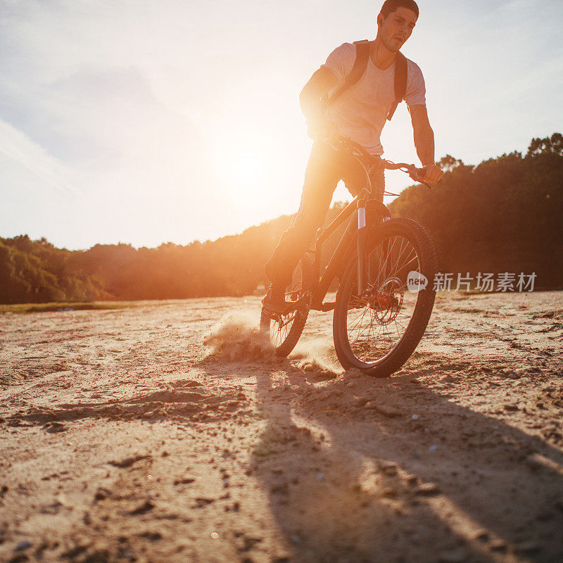 日落时分，骑自行车的人沿着海滩骑行
