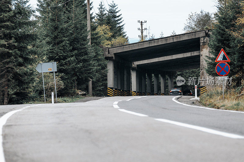 汽车在混凝土桥下的双车道道路上行驶