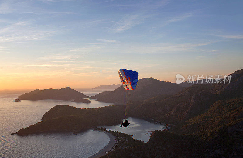在土耳其Oludeniz的蓝色泻湖上空，在日落时飞行的滑翔伞