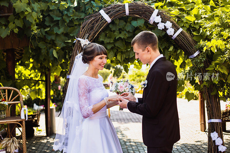 新郎和新娘身穿白色礼服，背景是拱门。婚礼仪式。幸福的家庭