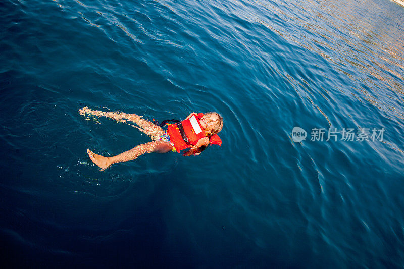 穿着救生衣在海里游泳的女孩