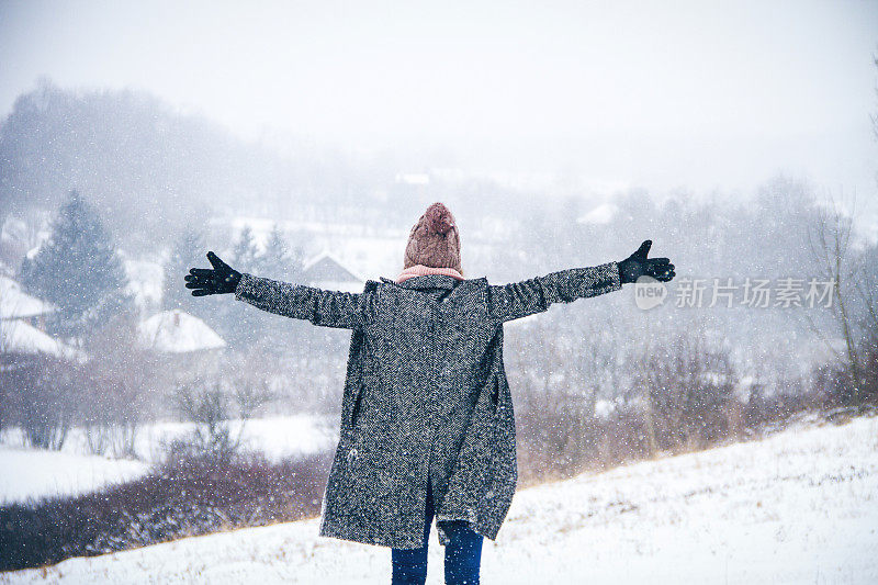 在雪地上举起手的女人