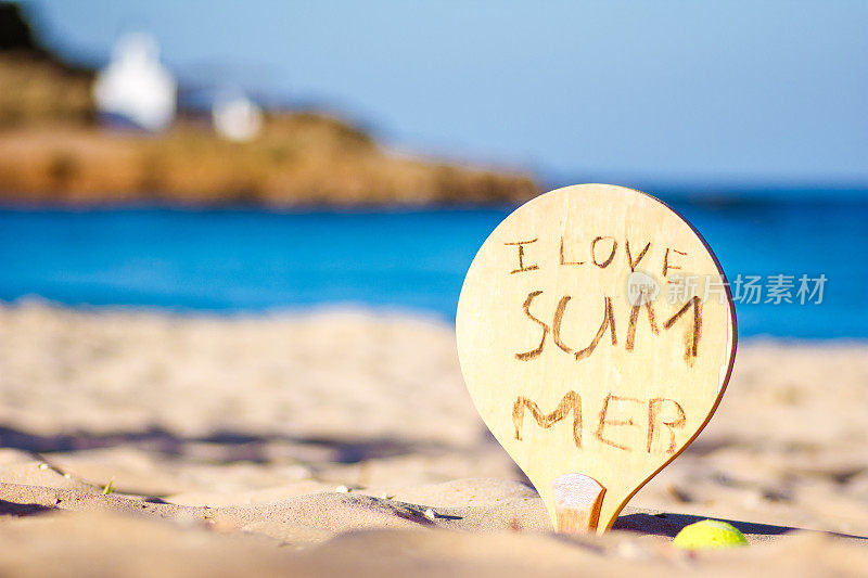 希腊克里特岛海滩上的一个网球拍，上面写着“我爱夏天”。