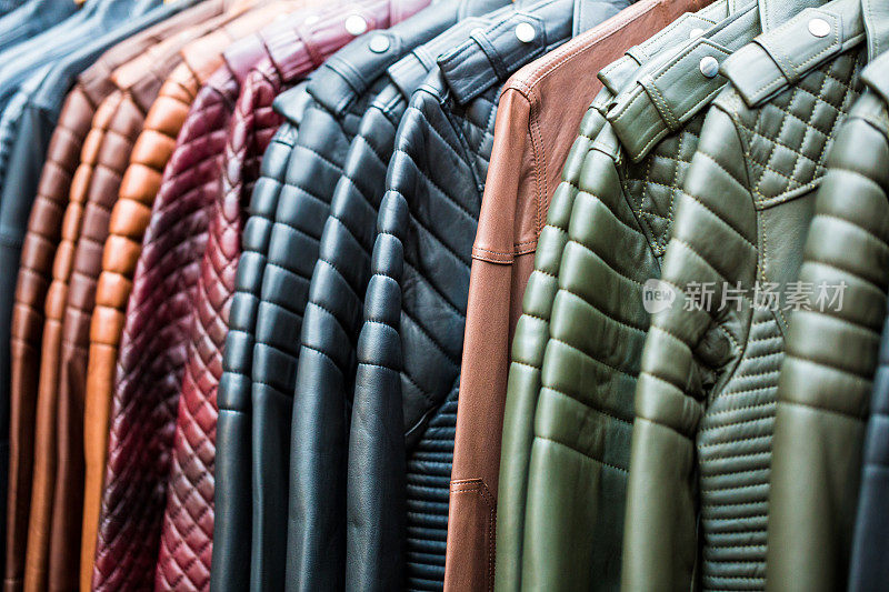 近距离收集的手工多色皮夹克挂在一排，并在服装市场出售