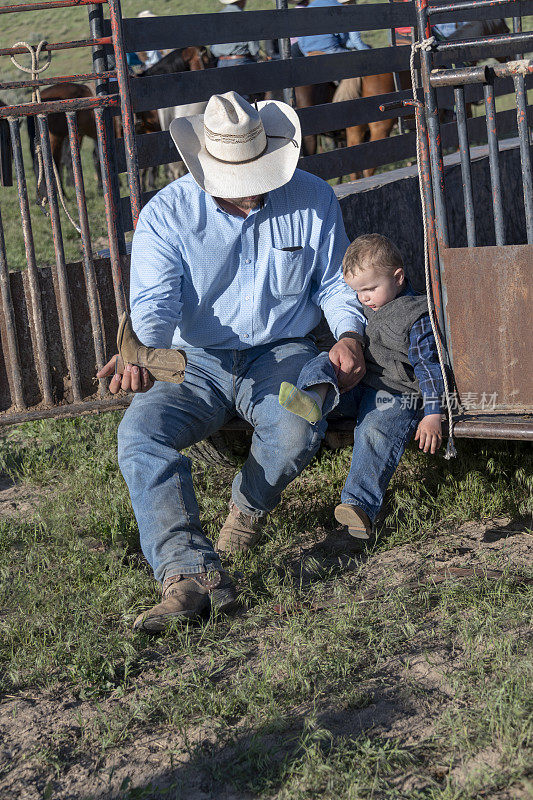牛仔爸爸帮小儿子穿靴子