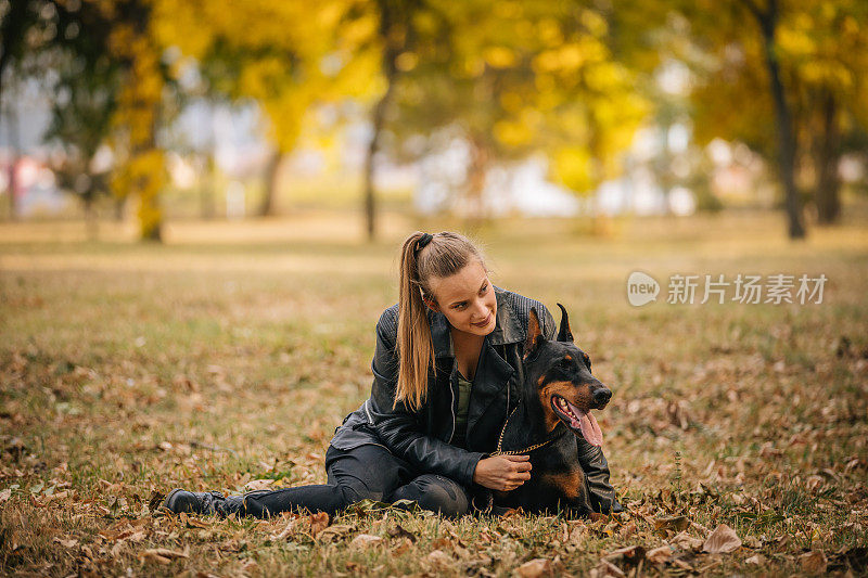 一个女人在公园里和她的杜宾犬玩耍