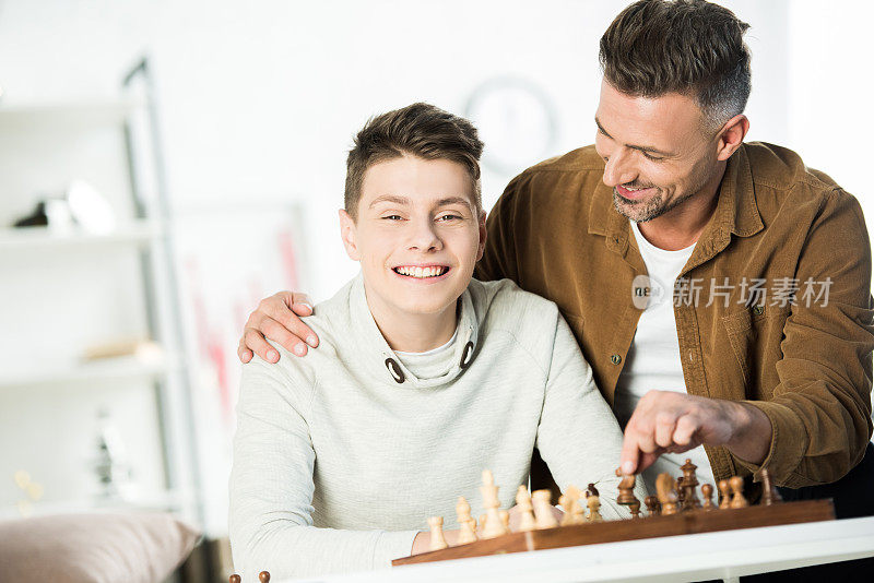 父亲拥抱快乐的儿子在桌上下棋在家
