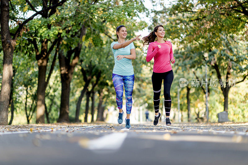 两个女性朋友在阳光公园的小路上慢跑