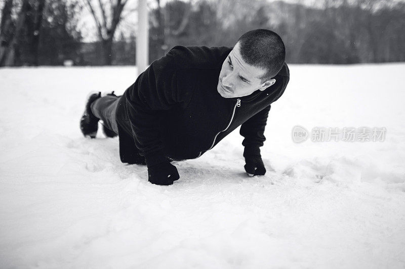 年轻人在雪地里做俯卧撑。