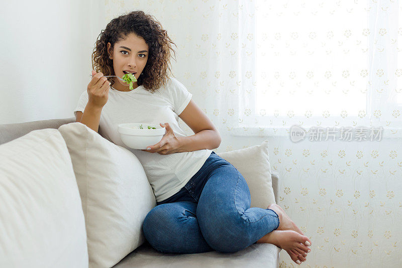 年轻女子吃新鲜的沙拉