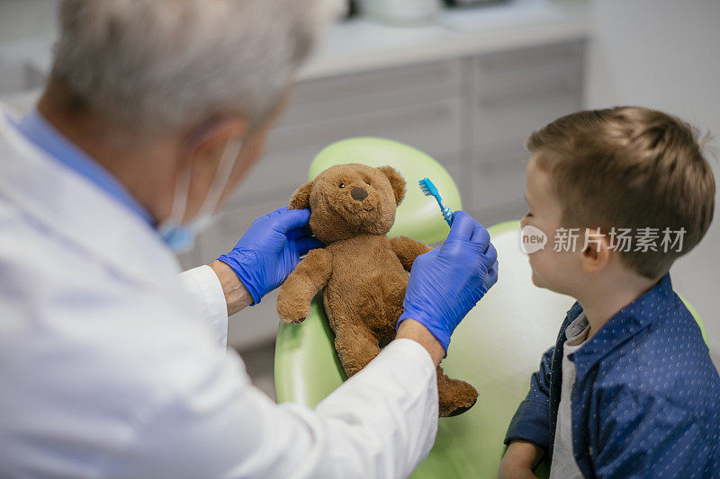 孩子在看牙医，玩具熊在玩牙刷