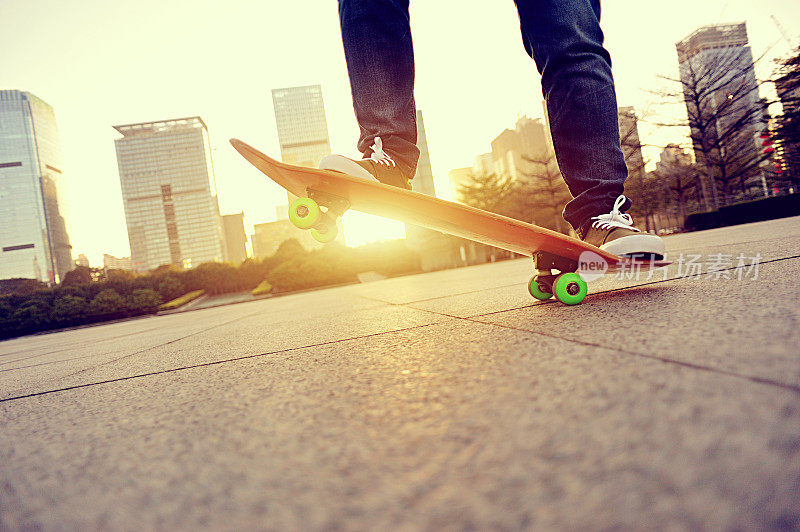 滑板者的腿在日出城市滑板