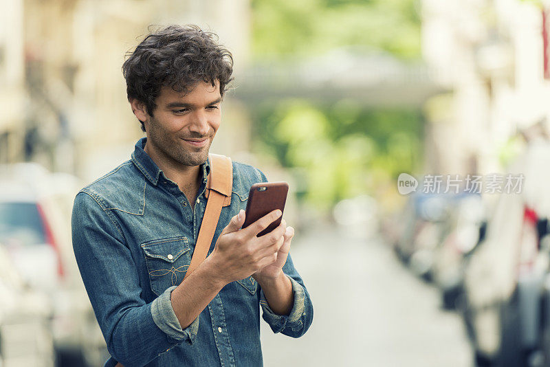 快乐的男人在街上用手机发短信。