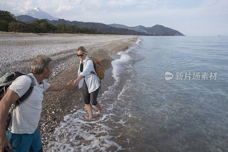 在卵石滩上，男人向女人伸出了援助之手