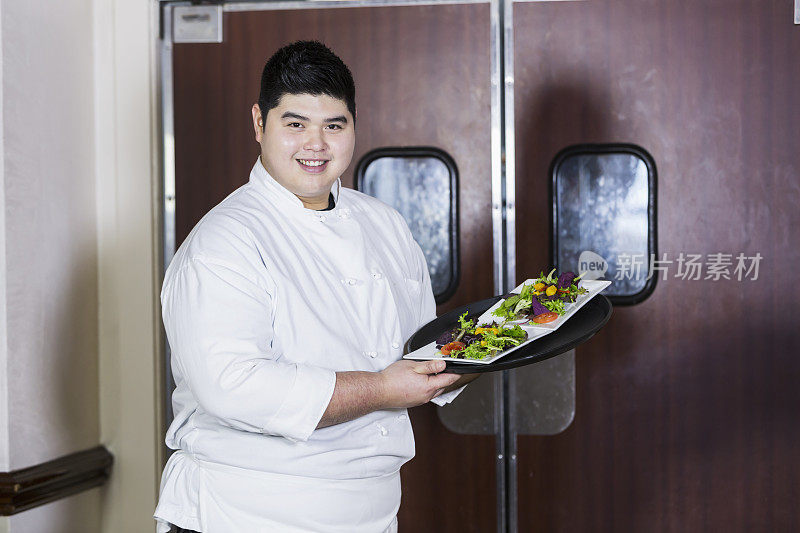 亚洲厨师或服务员在餐厅中端着食物托盘