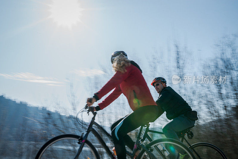 活跃的夫妇在风景优美的道路上骑自行车。