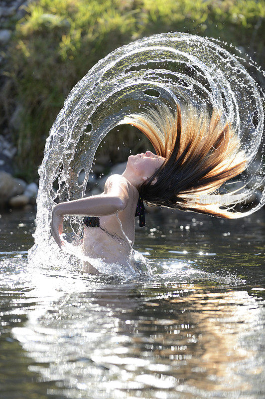水从年轻姑娘的头发上垂直飞起
