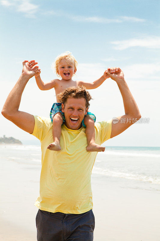 快乐的父亲和他的小儿子在海滩上玩