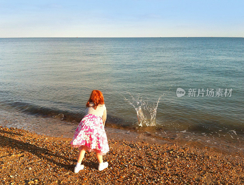 英国，朴茨茅斯海滩上的女孩把石头扔进海里