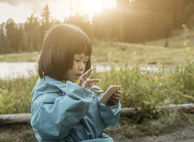 亚洲小女孩在雷尼尔山使用智能手机