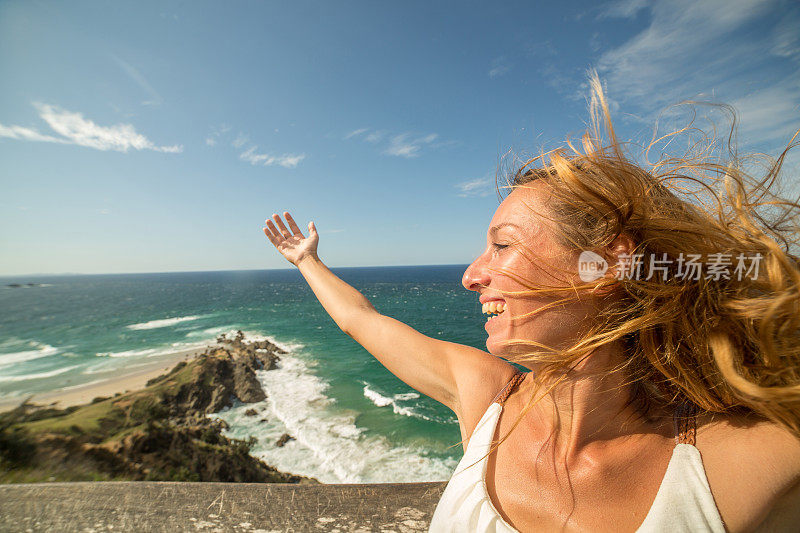 在海边吹头发的微笑年轻女人的肖像