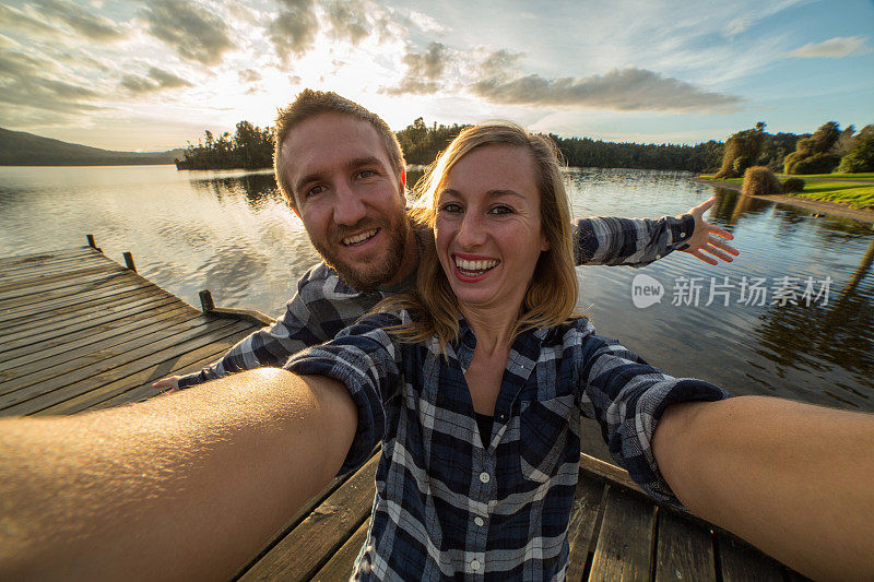 一对年轻夫妇在湖上的码头上自拍
