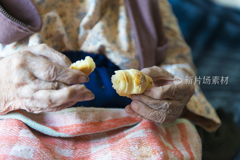 一个拿着羊角面包的老女人的手