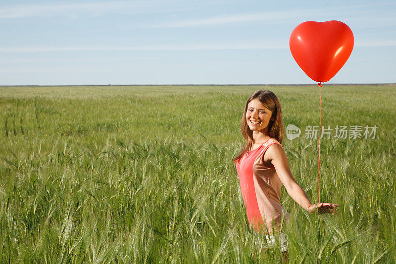 拿着红色气球的女孩站在操场上