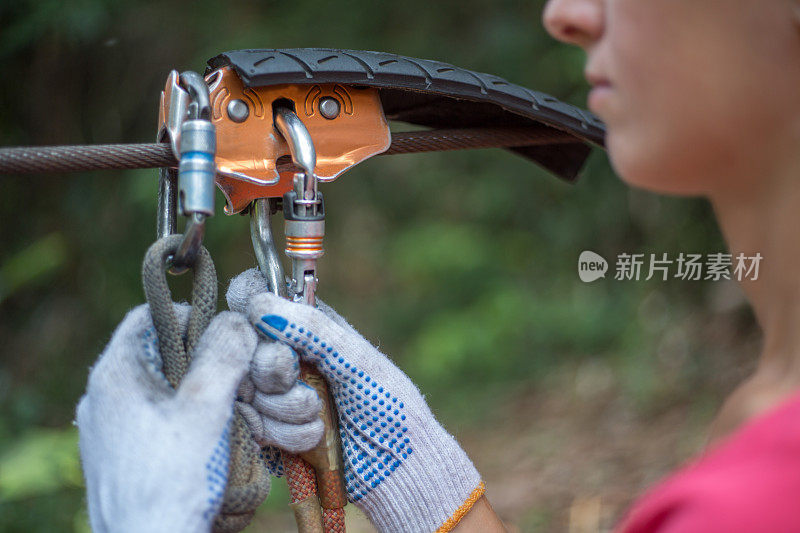 女人把滑索设备挂在钢索上