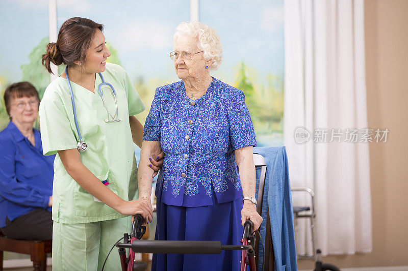 照顾拉丁后裔护士帮助老年病人使用她的助行器。
