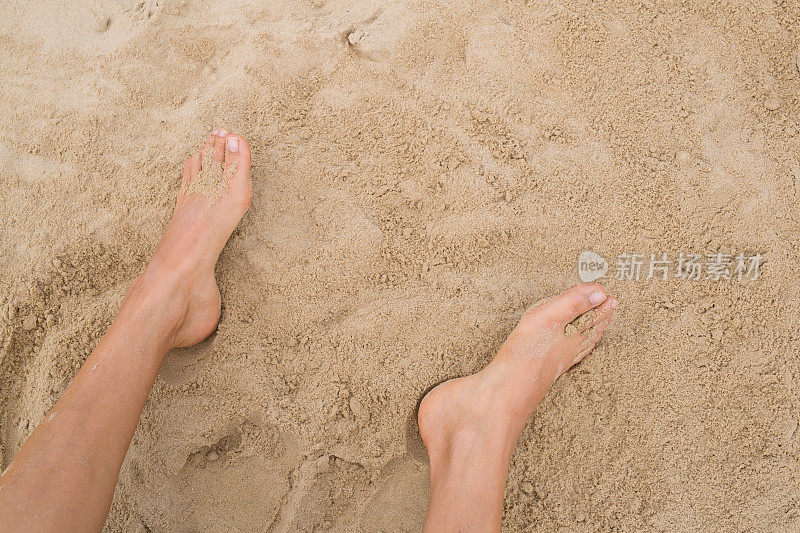 两只雌性的脚踩在沙滩上
