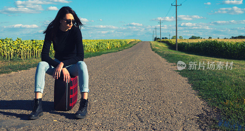 年轻女子在空旷的路上搭便车