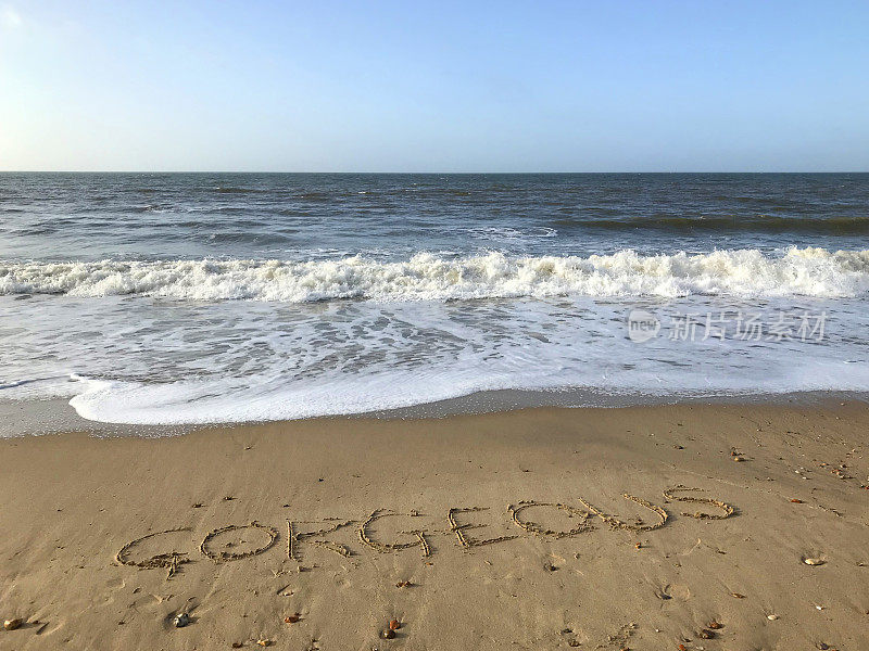 图片写在阳光沙滩上华丽的字写在沙子上，用棍子，海浪，概念社交媒体照片在柔软的金色沙滩上书写字母，多塞特，英国海边的海岸线