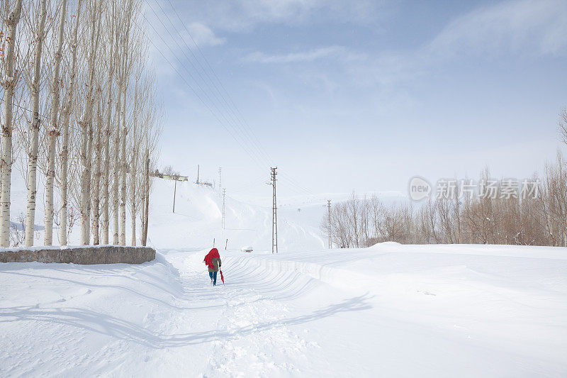 成年妇女穿着暖和的衣服在雪地上行走在农村