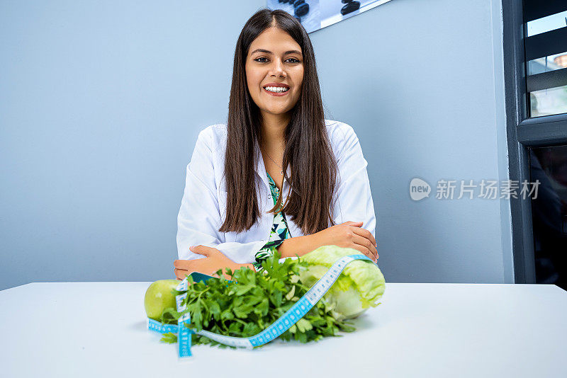 营养学家看着摄像机和餐桌上的健康蔬菜