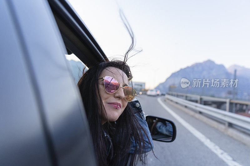 年轻女子坐在车里，车窗开着，眼睛望着别处