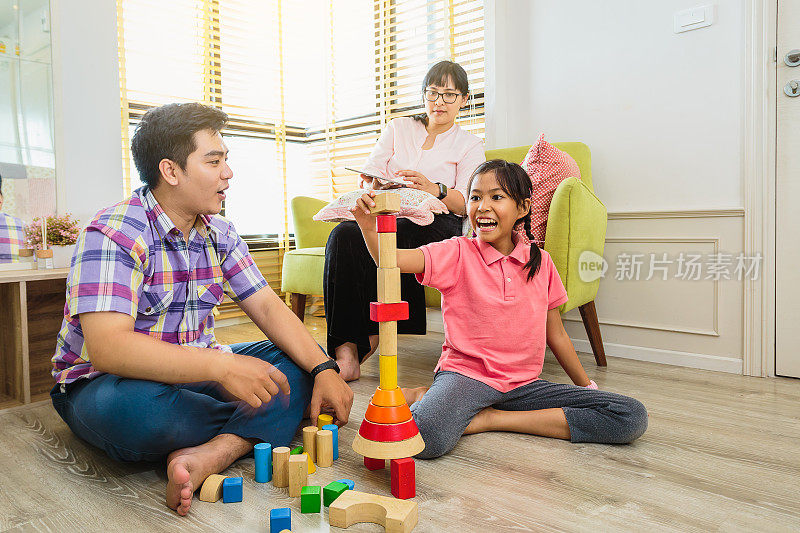 快乐的亚洲家庭玩玩具积木和花时间一起在家里的客厅