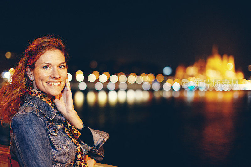 快乐的年轻红发都市女性夜间肖像在布达佩斯