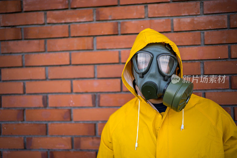 一个穿着防护服戴着防毒面具的人站在一堵墙前