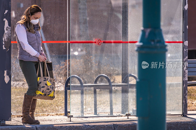 戴着口罩的女人在等车。