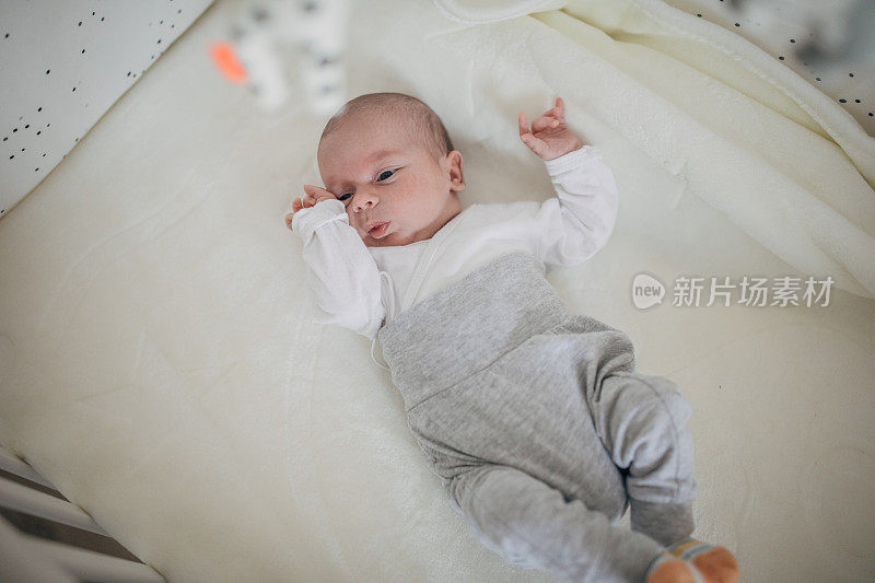 刚出生的男婴躺在婴儿床上