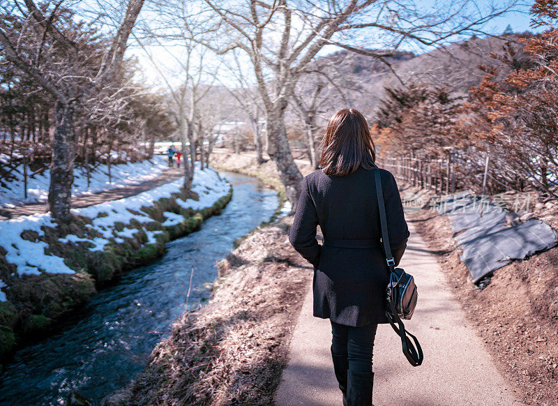 美丽的女人散步和享受自然景观在村庄与白雪冬天，日本