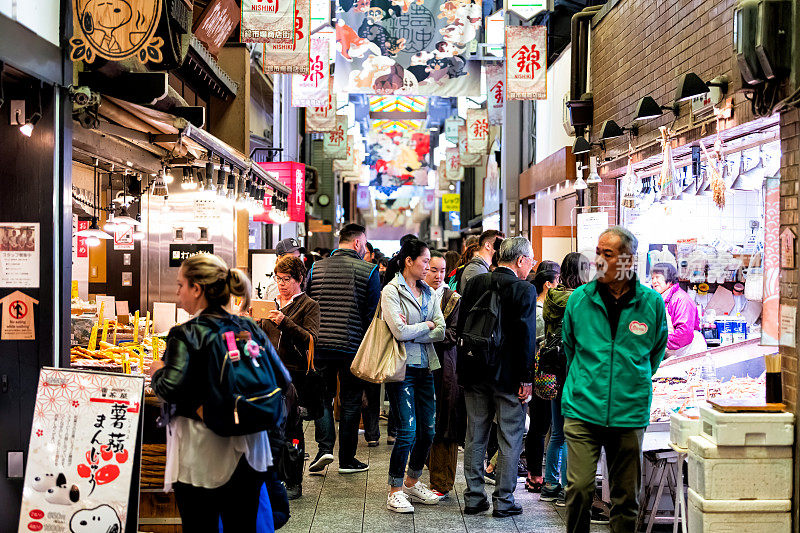人们在京都西城市场购物，拱廊上有商店、餐馆和食品摊贩