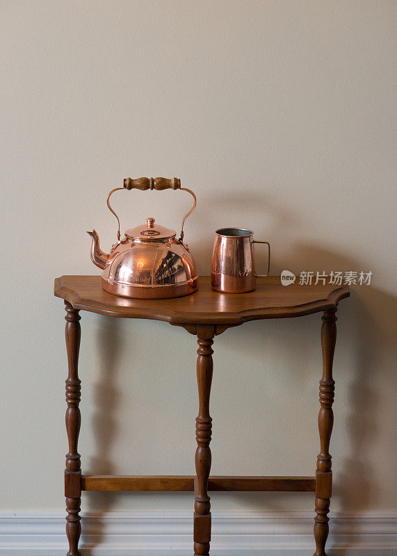 傍晚的阳光下，胡桃木边桌上的古董铜茶壶和茶杯