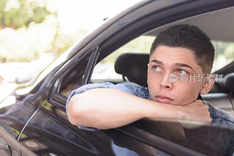 一个年轻人从汽车后座的窗户往外看
