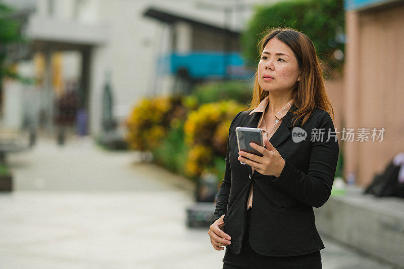 一位亚洲女商人在城市街道上使用手机