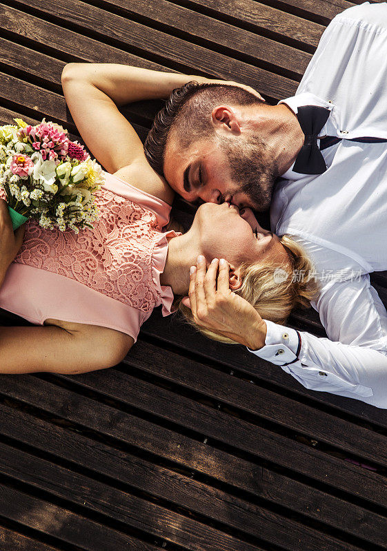 新娘和新郎躺在木地板上亲吻
