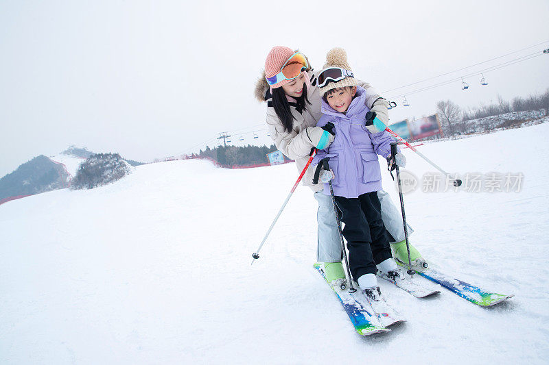 滑雪场上抱在一起滑雪的幸福母女